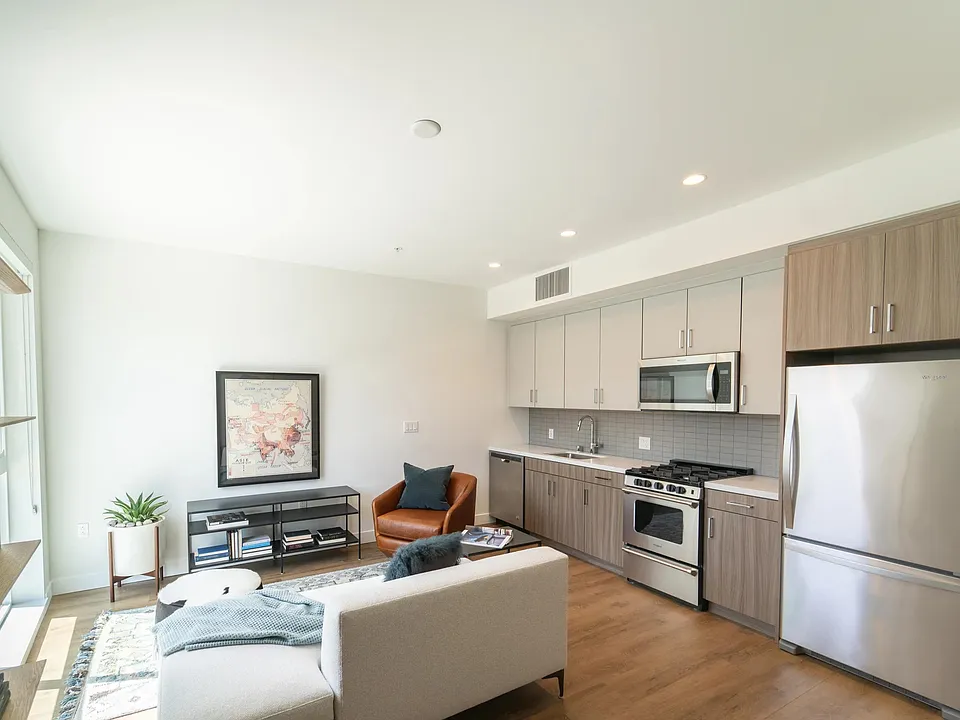 Open-concept home with dual-tone cabinetry, stainless steel appliances, and wood-style plank flooring flowing through a bright, efficient living space.