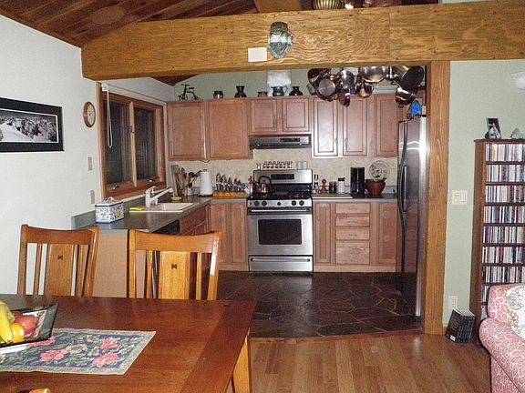Kitchen is open to dining and living room space, with hanging pots and pans.