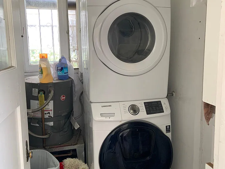 Stack washer and dryer in laundry room that leads out to the parking lot