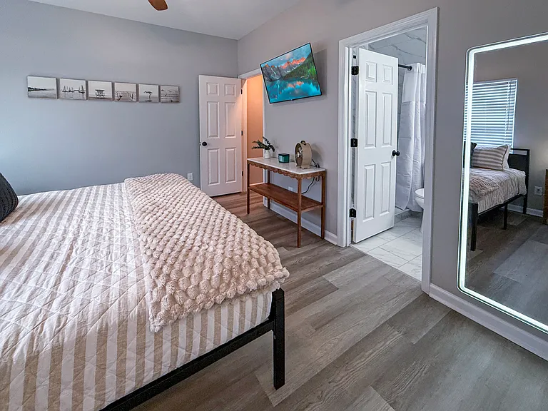 Primary King bedroom downstairs with RoKu Smart TV, direct access to bathroom and upgraded features such as touch screen full-length lighted mirror
