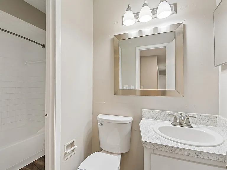 Bright and modern bathroom featuring a sleek white vanity, stylish mirror, and inviting bathtub, offering a refreshing oasis for relaxation.
