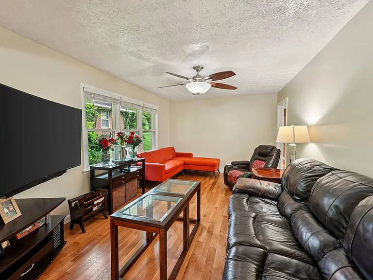 A warm and inviting living room where polished hardwood floors, soft window light, and cozy seating create a charming retreat for quiet evenings and everyday comfort.