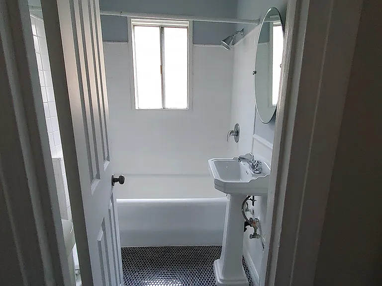 tiled floor with reglazed tub and tiles, toilet behind door