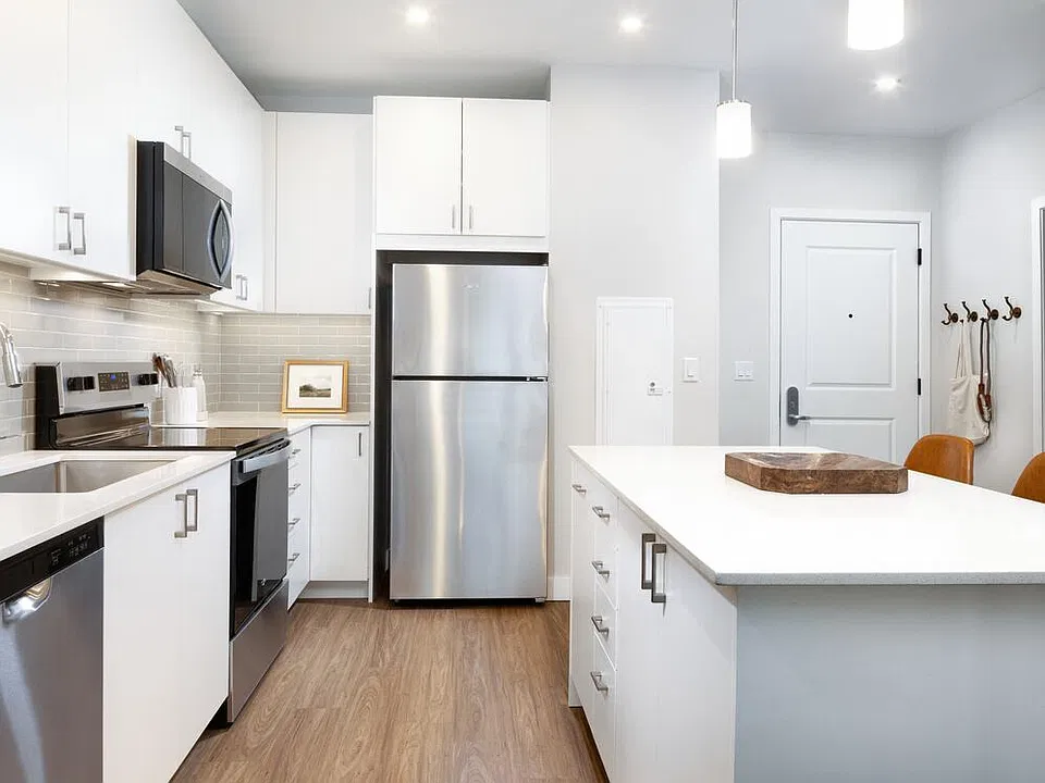 Design Collection I kitchen with stainless steel appliances, white cabinetry, grey tile backsplash, under-cabinet lighting, white quartz countertops, and hard surface flooring