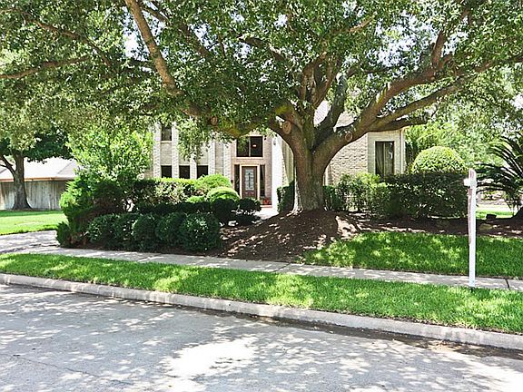 Front of house nestled behind circle drive and enormous Live Oak