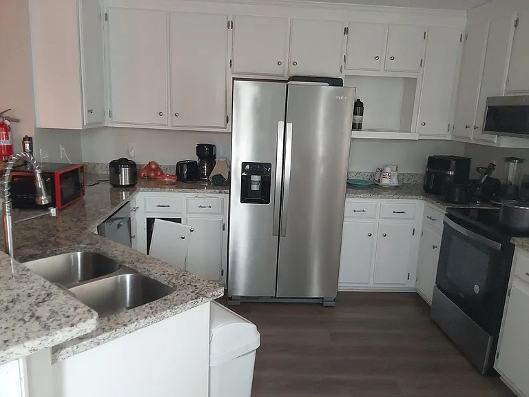 U-shaped kitchen with generous counter space, ample cabinetry, and stainless appliances including a side-by-side fridge.