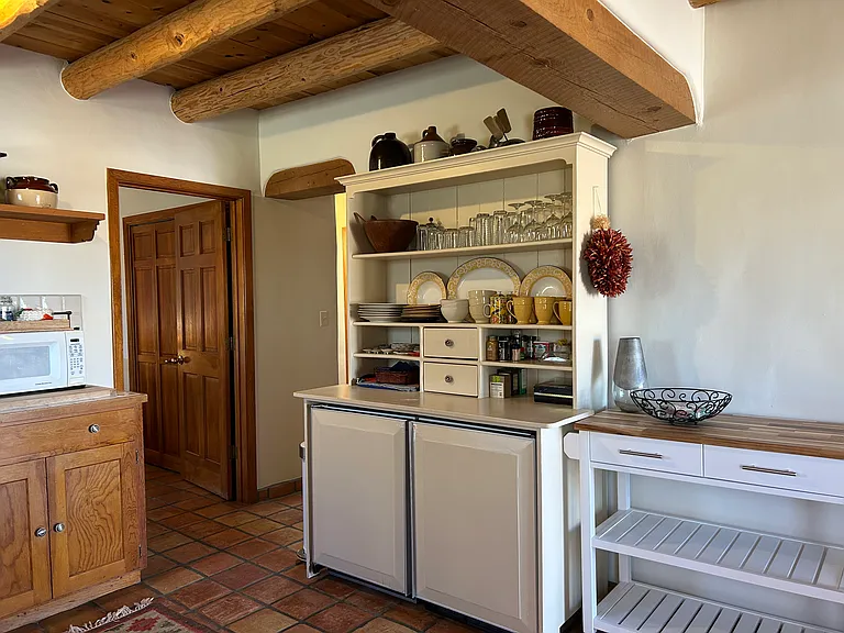 Nambe Casita kitchen showing hutch and rolling kitchen island. View looks towards the bedroom door on the right and the hall leading to the bathroom and laundry room on the left.