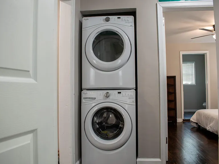 Convenient in-home laundry closet with stacked front-load washer and dryer, located off the hallway near the bedrooms.
