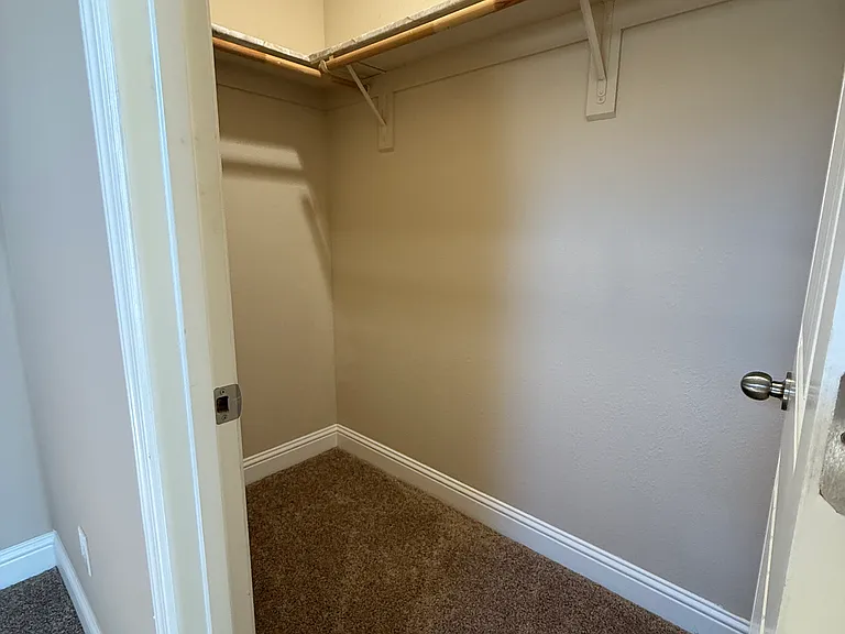 Bedroom walk in closet with small storage space above.