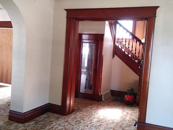 This is the second large living space. Notice the original woodwork. The mirrored door allows everyone to check their appearance before leaving the house as well as hiding the secret reading room and coat closet. The Shopvac does not stay.