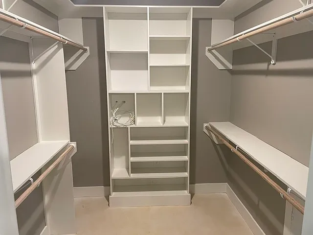 Primary bedroom closet with plenty of space and built in shelving.