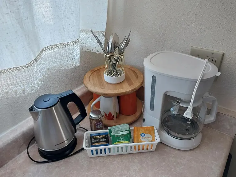 Coffee pot and hot water kettle provided in kitchen.