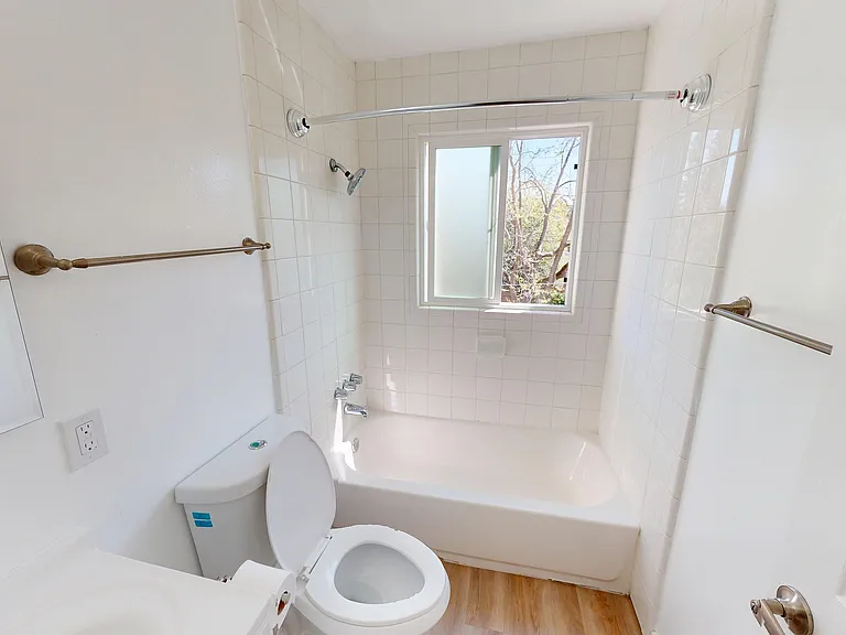 Bright and airy bathroom with elegant fixtures, white tile walls, and a window allowing natural light. Bright and airy bathroom with elegant fixtures, white tile walls, and a window allowing natural light.