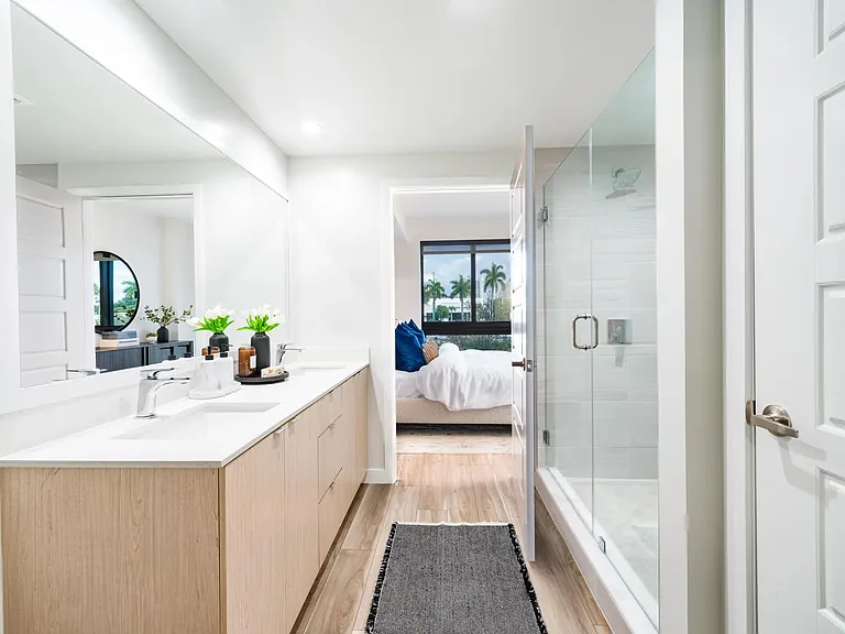 Spa-inspired bathroom design features clean lines, warm wood cabinetry, and glass-enclosed showers_bringing a calm, coastal feel to Modera Aventura homes.