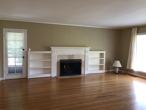 Living room with hardwood floor, door to deck and fireplace.