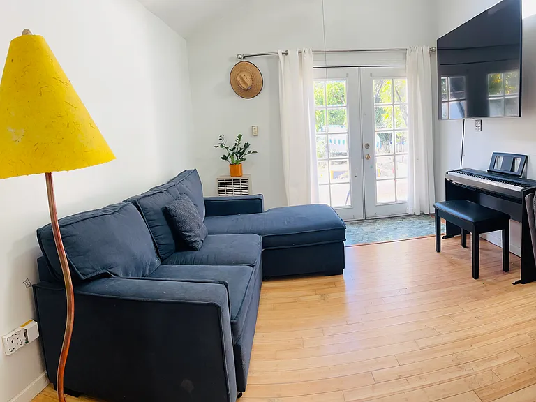 Master bedroom with french doors leading to the backyard. May also be set up as a secondary living room space. Attached full size bathroom to the right, large sky light and high ceilings.