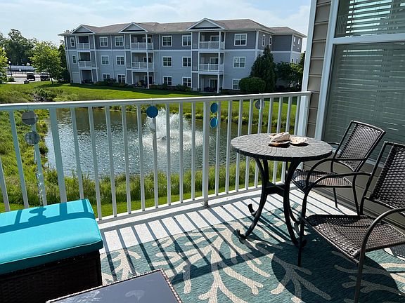 Patio with chairs and a table and also a couch with the pond view