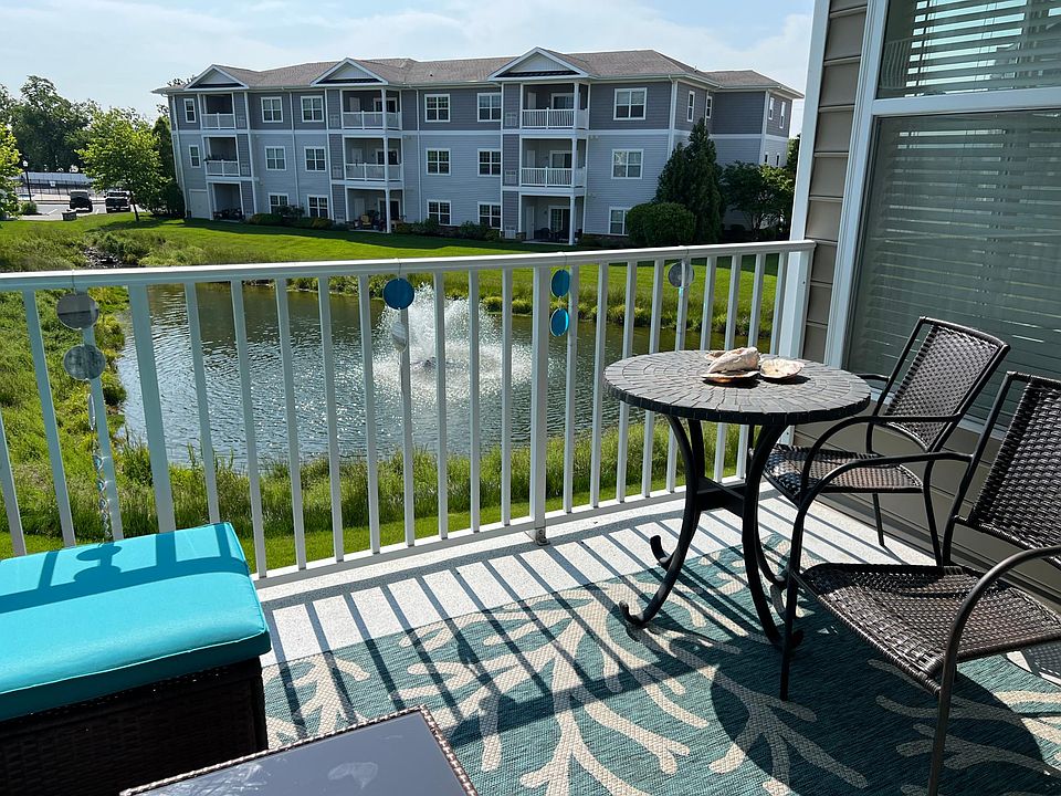 Patio with chairs and a table and also a couch with the pond view