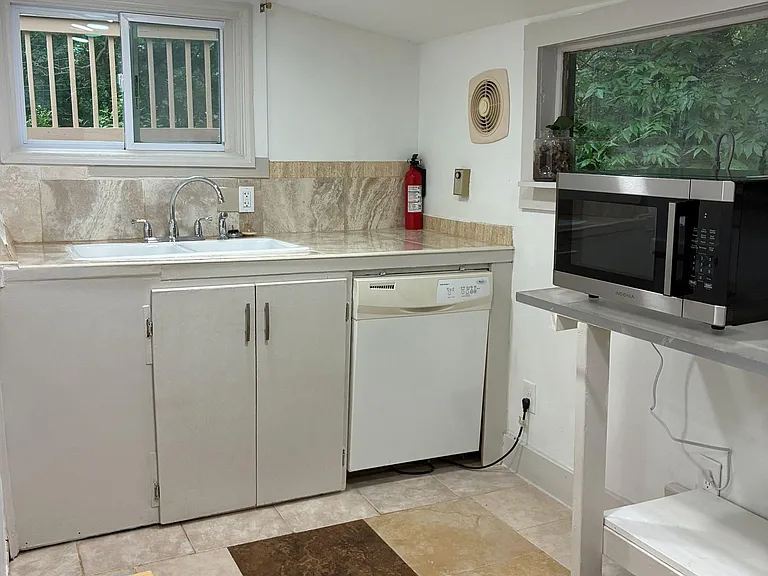 Functional kitchen with sink, dishwasher, and generous counter space, plus windows for natural light and outdoor views.