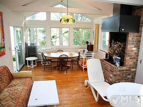 Large dining room with seating area, indoor grill with chimney, views of the lake and sliders to the deck.