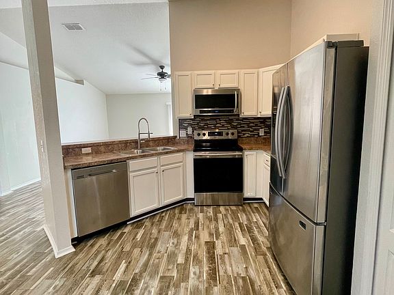 Kitchen featuring matching Samsung stainless steel appliances, white cabinetry and tile backsplash.