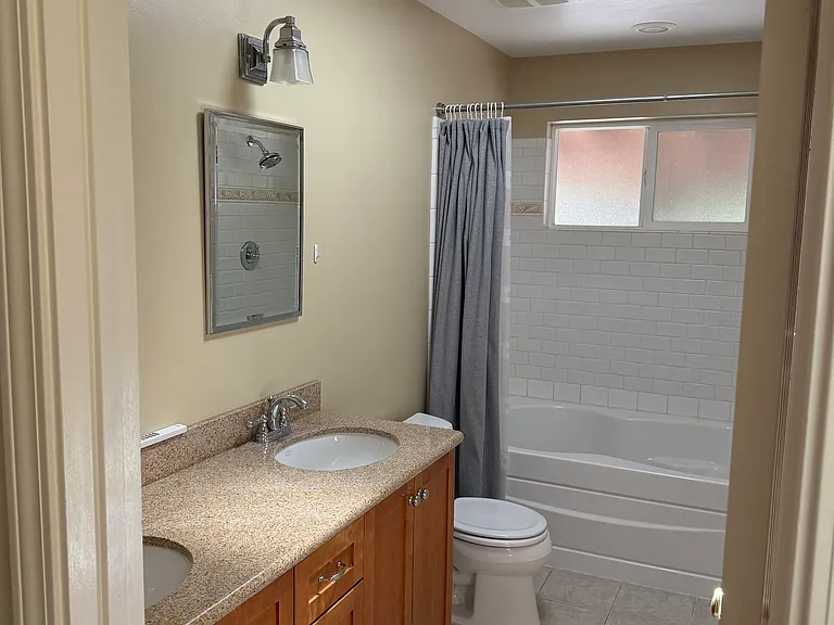 bathroom with dual vanity and large tub