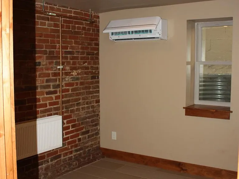 Bedroom with mini ductless AC/heat unit on wall.