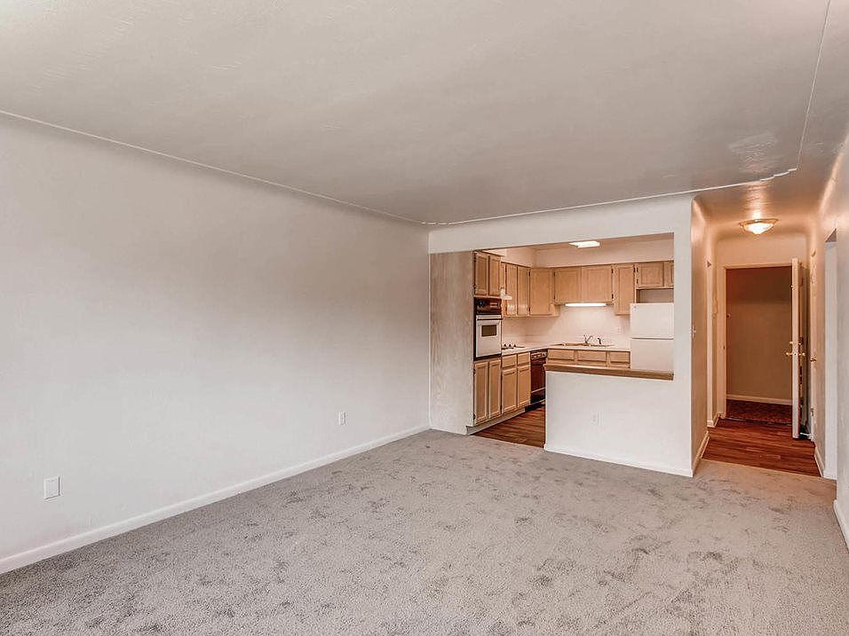 Royal Gardens - Spacious living room with plush carpeting and a view of the kitchen.