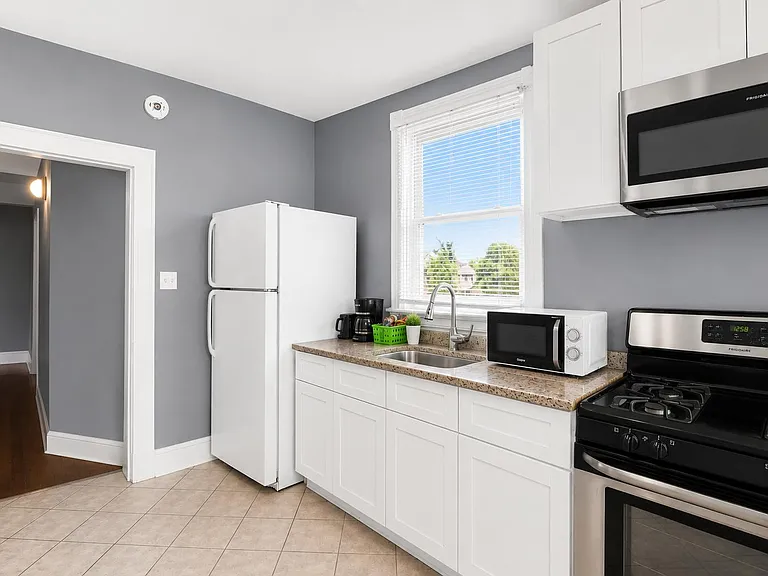 Efficient kitchen with white cabinetry, ample counter space, stainless gas range, and a window over the sink.