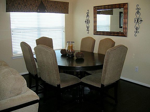 Elegant dining room has wood type flooring, bright window, contemporary lighting