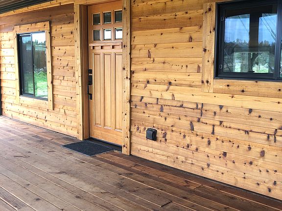 Covered front porch with view of kitchen and living room windows.