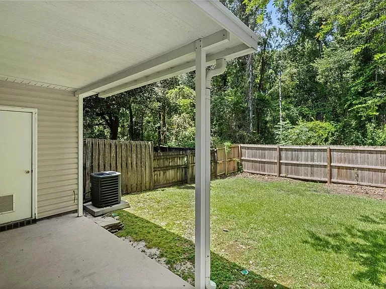 Covered patio area with a concrete slab, featuring vinyl siding and a rear entry door