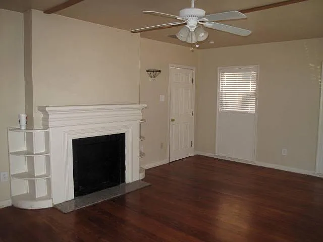 Large living room with beautiful hardwood floors, mock fireplace, custom shelves, and ceiling fan