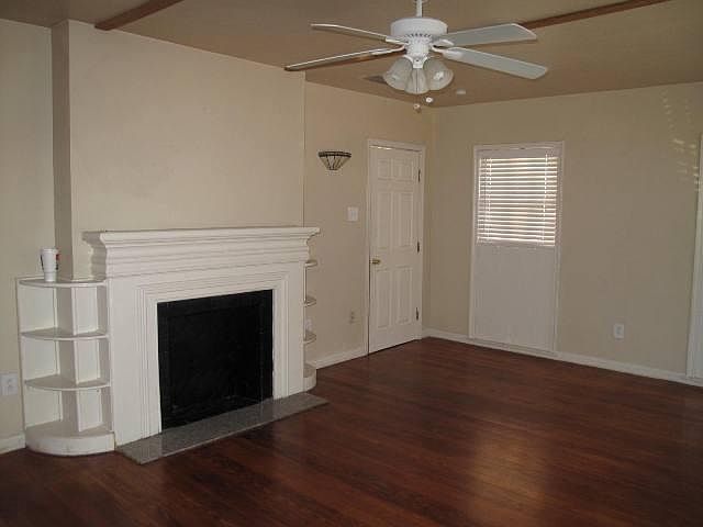 Large living room with beautiful hardwood floors, mock fireplace, custom shelves, and ceiling fan