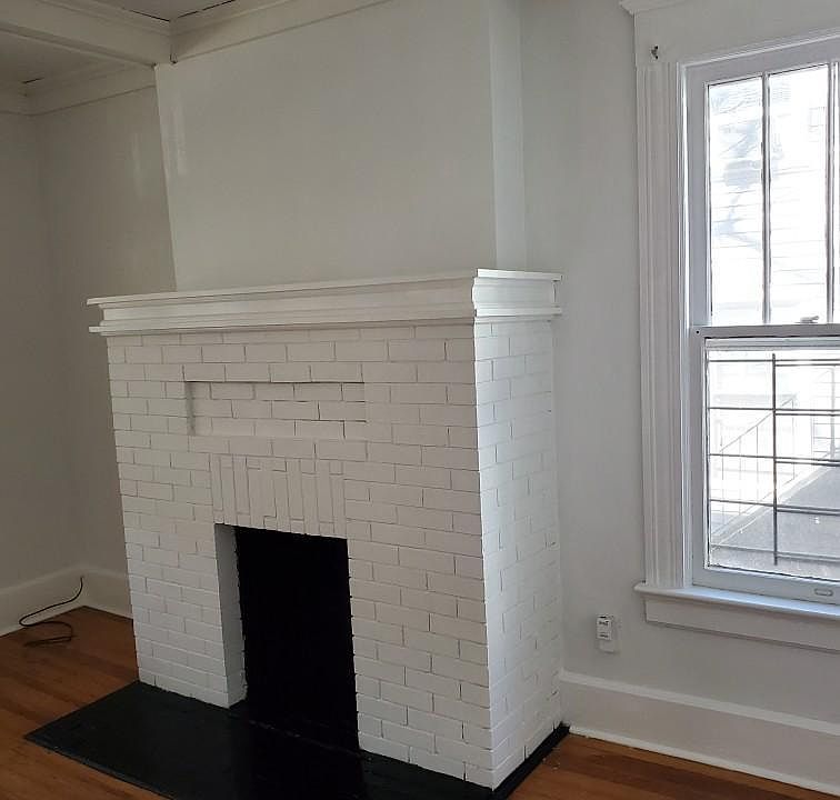 living room with fireplace, classic trim, lots of windows, hardwood floors