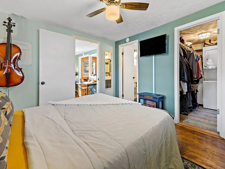 Bedroom looking into living room on left, bathroom in middle and closet/laundry on right