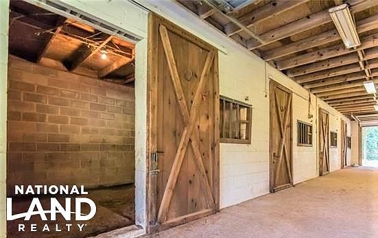 Show barn with 2 apartments above for potential rental income (1057 sqft and 1350 sqft),  8 stalls with solid doors, pads, lights, tack room, restroom, and two 975 sqft storage bays