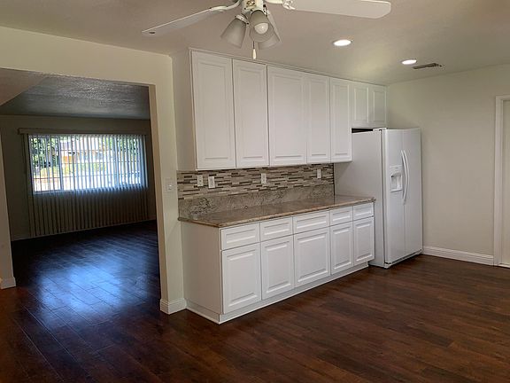 Kitchen with new cabinets and granite counters, tile backsplash is open to dining area and living room. Refrigerator is included.
