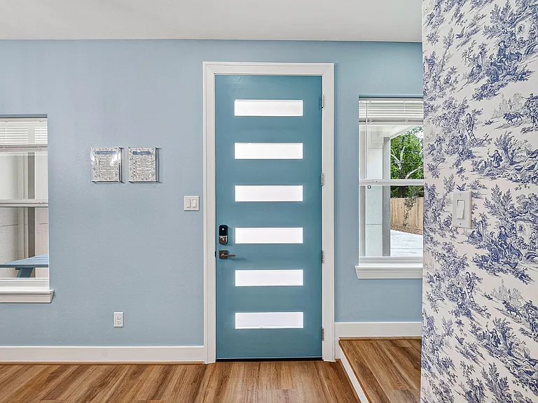 Inviting entry area with a contemporary front door, durable wood-look flooring, and windows that bring in natural light.