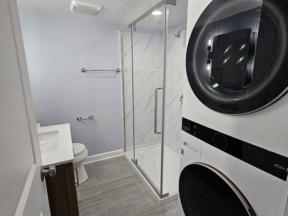 bathroom with stackable front loading washer and dryer