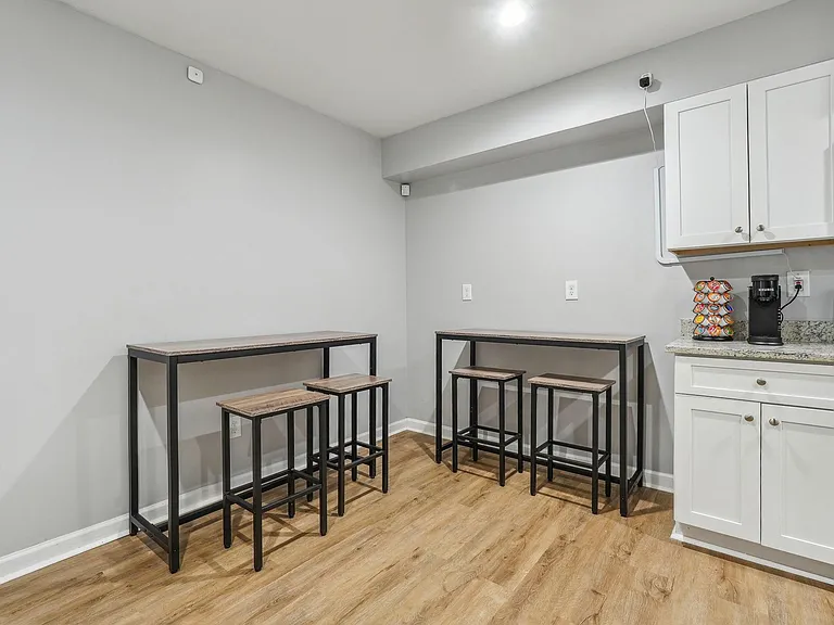 Eat-in kitchen area with two bar-height tables and stools, set beside ample cabinetry and countertop workspace.