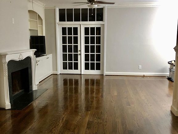 Living room with hardwood floors and fireplace; French doors open to a large patio with bird feeder & private view of Nancy Creek.