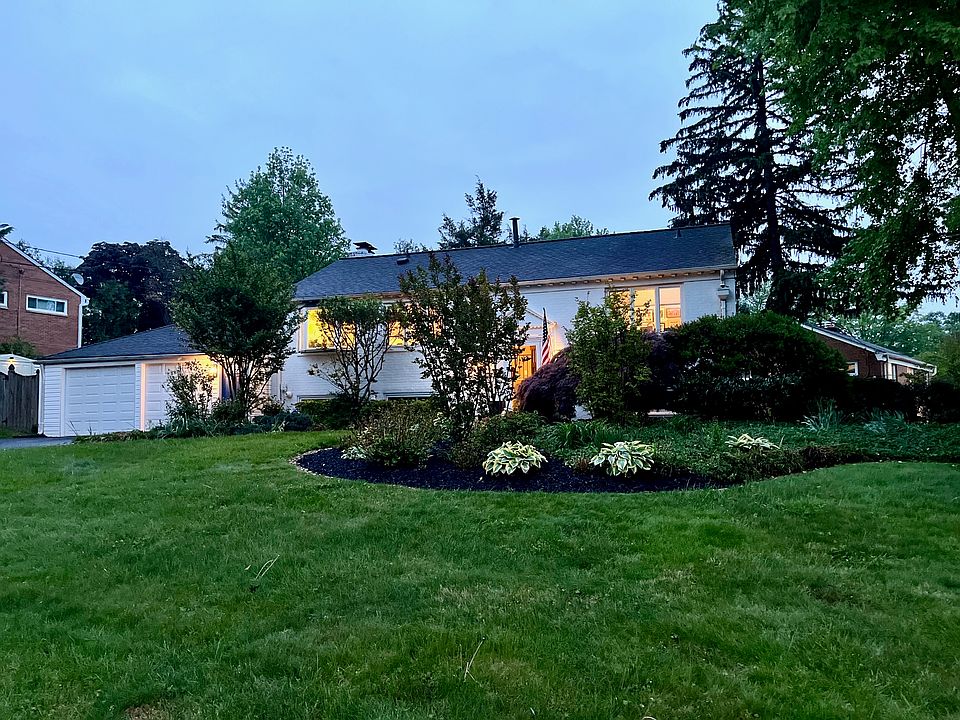 Front exterior of home, garage, and landscaped garden and front yard at dusk.