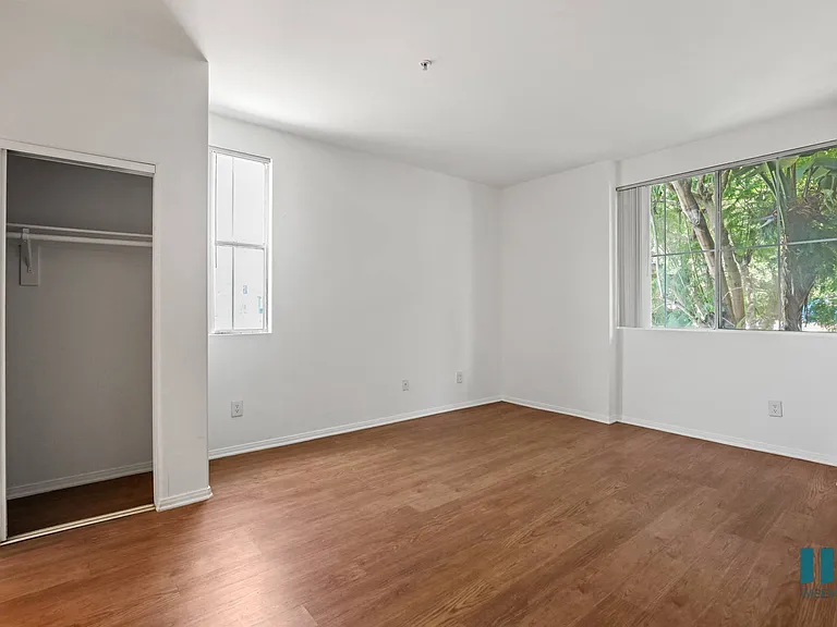 Bedroom with Large-Size Windows, Mirrored Closet, and Vinyl Flooring