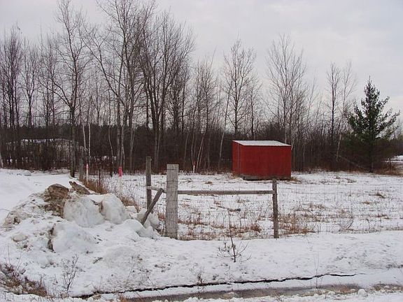 This pasture is l-shaped with a animal shelter within the fenced area.