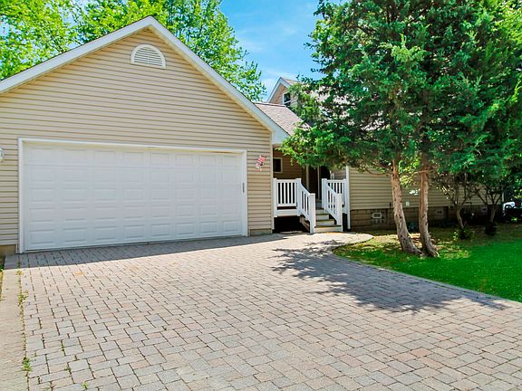 side of the home with brick paver driveway and covered patio