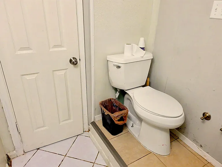 Compact bathroom with tiled flooring, standard toilet, and easy access via a paneled interior door.