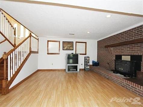 Lower level family room with laminate flooring and woodburning brick surround stove/ fireplace.