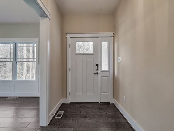 A white front door with glass panels in a beige entryway at Poplar Village, beside a room with large