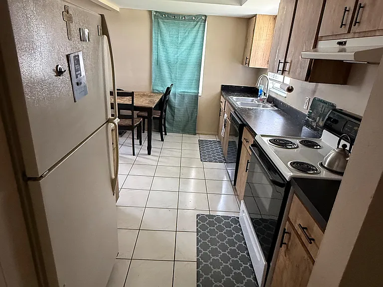 Galley kitchen with ample cabinetry, full appliance set, double-basin sink, and adjacent dining nook by the window.